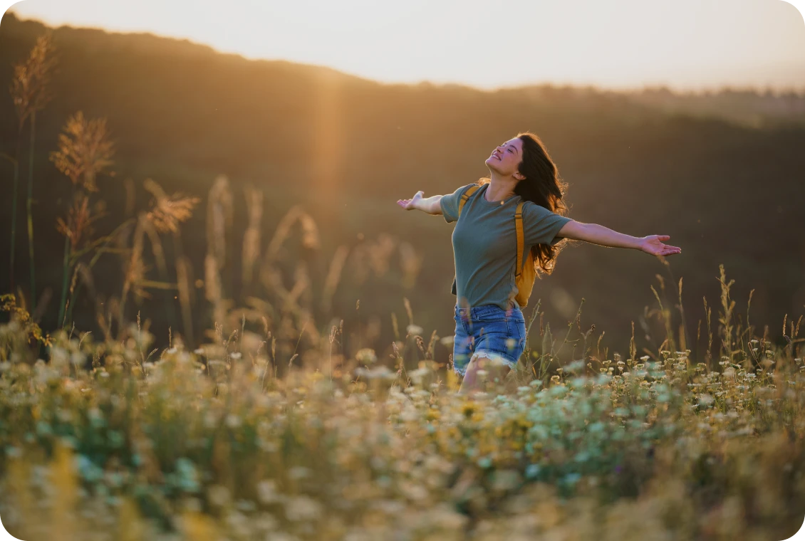 Happy woman with open arms in meadow